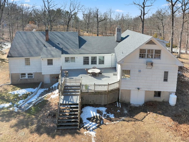 back of house featuring a deck, roof with shingles, stairway, and a chimney