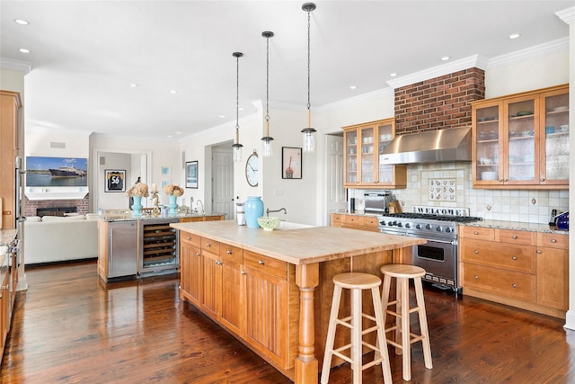 kitchen with wall chimney exhaust hood, high end range, a kitchen breakfast bar, a kitchen island, and beverage cooler