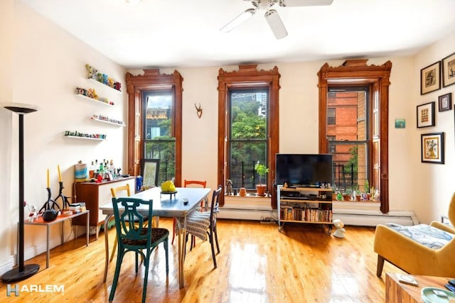 dining space featuring a baseboard heating unit, ceiling fan, and light hardwood / wood-style flooring