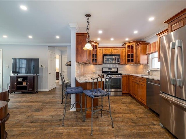 kitchen featuring crown molding, appliances with stainless steel finishes, a breakfast bar area, and hanging light fixtures