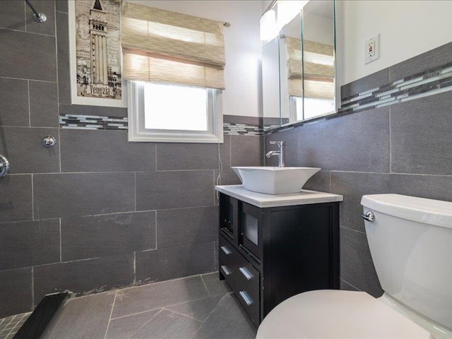 bathroom with vanity, toilet, tile walls, and a shower