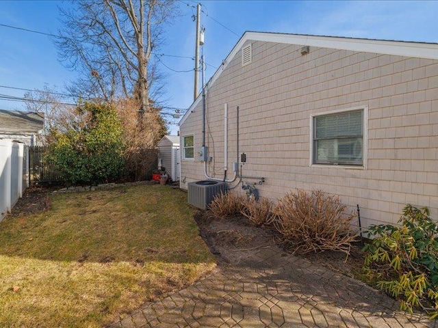 view of side of property featuring central AC and a yard