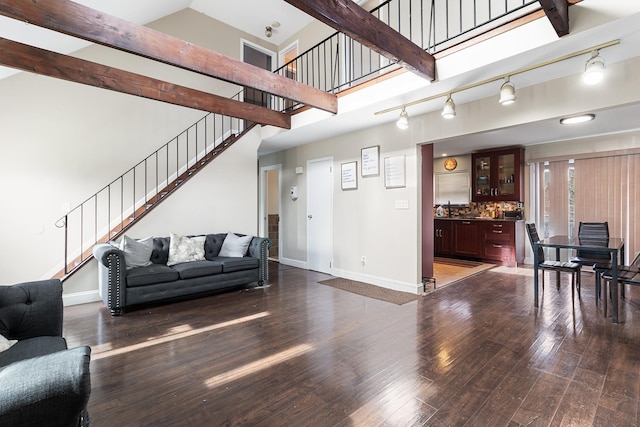 living room featuring beam ceiling, dark wood-type flooring, and a high ceiling