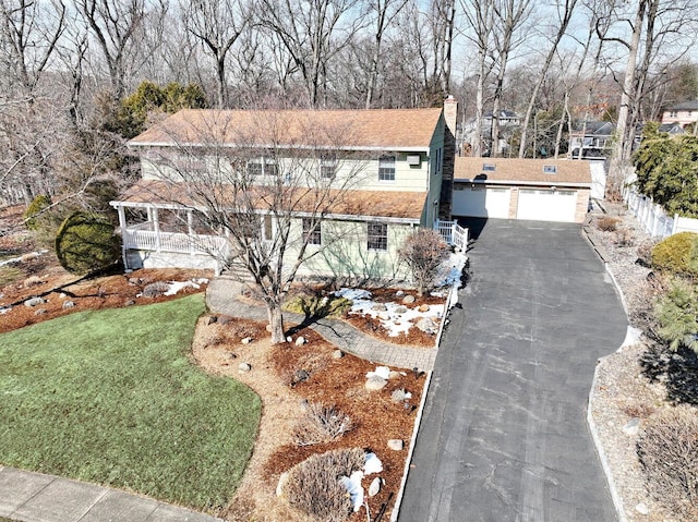 view of front facade with a detached garage, a chimney, fence, and a front yard