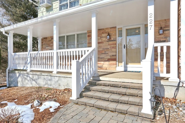 property entrance with stone siding and a porch