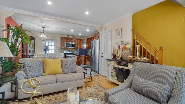 living room featuring crown molding, a chandelier, and light wood-type flooring