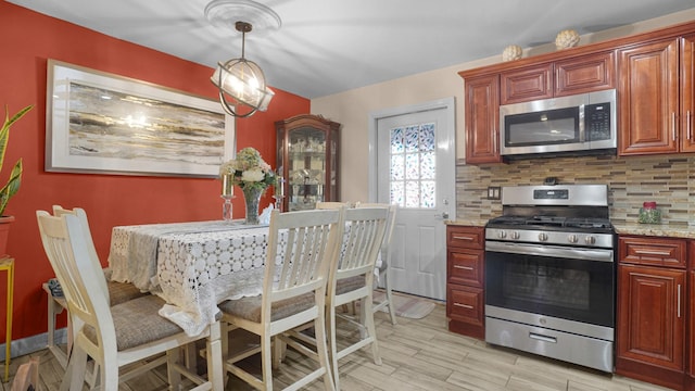 kitchen with stainless steel appliances, pendant lighting, light stone counters, and decorative backsplash