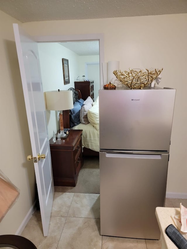 tiled bedroom with a textured ceiling and stainless steel refrigerator