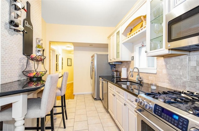 kitchen featuring sink, white cabinetry, light tile patterned floors, appliances with stainless steel finishes, and decorative backsplash