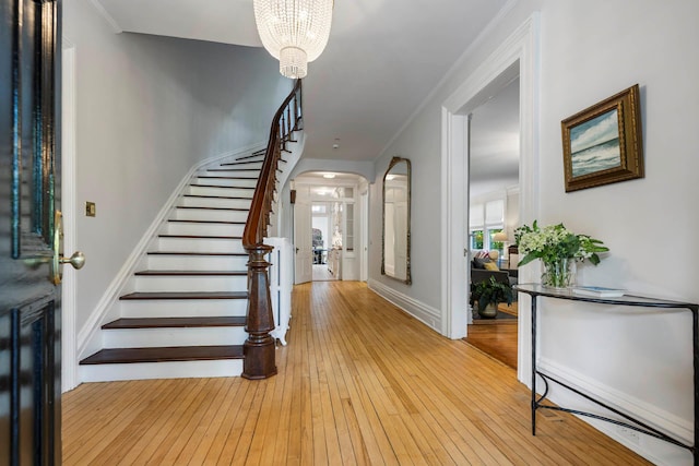 157 Merlin Ave, Sleepy Hollow, NY 10591 - foyer entrance with arched walkways, light wood finished floors, a chandelier, stairway, and crown molding