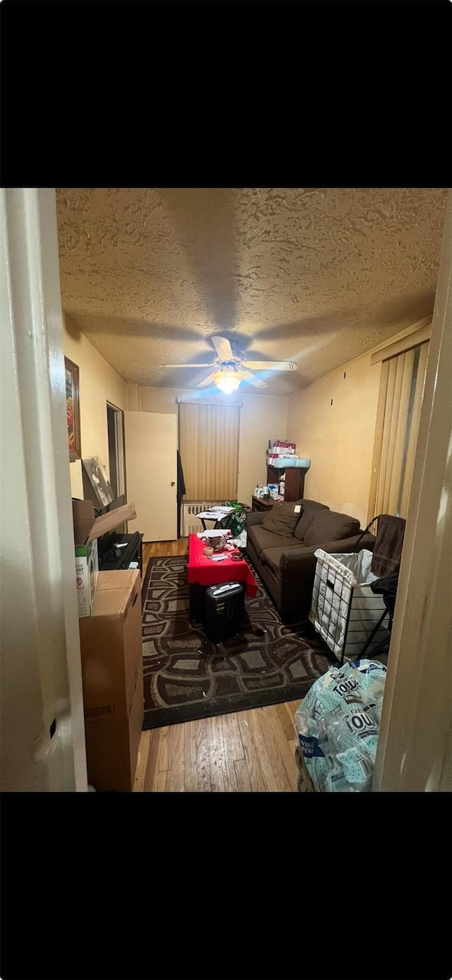 misc room with ceiling fan, hardwood / wood-style flooring, and a textured ceiling