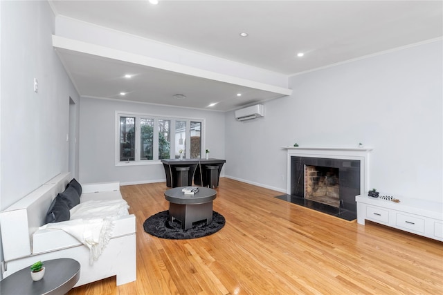 living room with a wall mounted air conditioner, ornamental molding, and light hardwood / wood-style floors