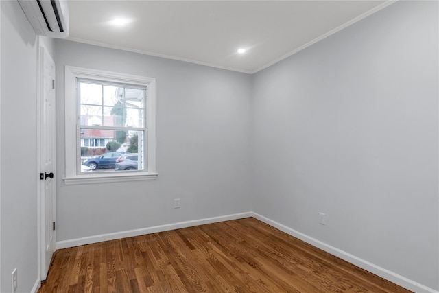 spare room featuring a wall mounted AC, hardwood / wood-style floors, and crown molding