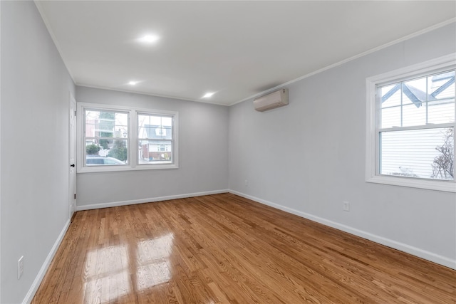 spare room featuring ornamental molding, a wall mounted AC, and light wood-type flooring