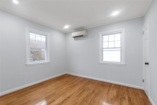 unfurnished room featuring crown molding, a wall mounted air conditioner, and light wood-type flooring