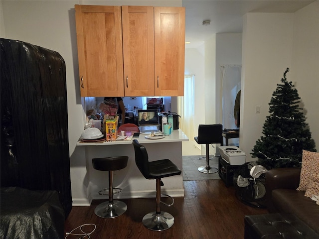 kitchen with dark wood-type flooring, kitchen peninsula, and a kitchen bar