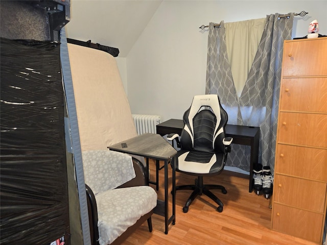 office with lofted ceiling, radiator, and hardwood / wood-style floors