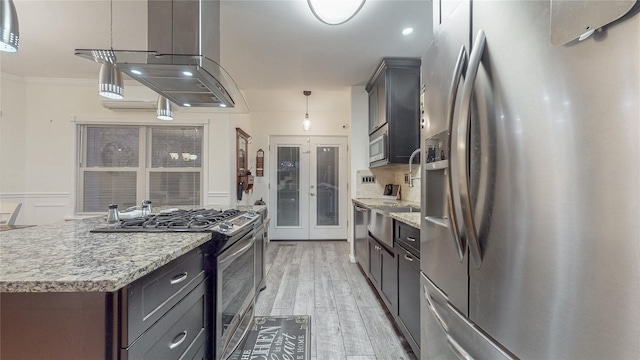 kitchen featuring island exhaust hood, stainless steel appliances, hanging light fixtures, a kitchen island, and light wood-type flooring