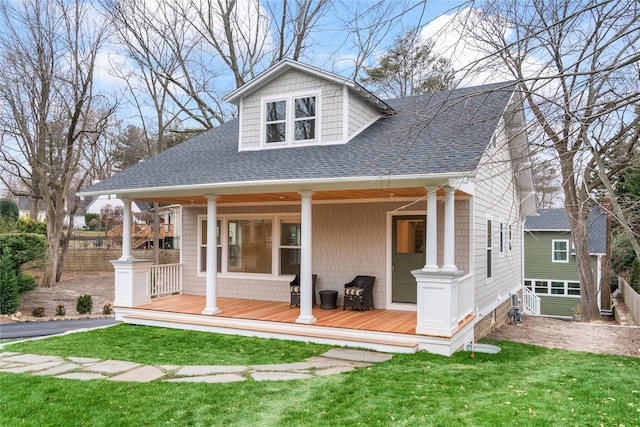 view of front of house with a porch, a front lawn, and roof with shingles