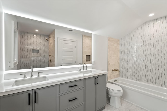 full bathroom featuring vaulted ceiling, tiled shower / bath, vanity, toilet, and tile patterned floors