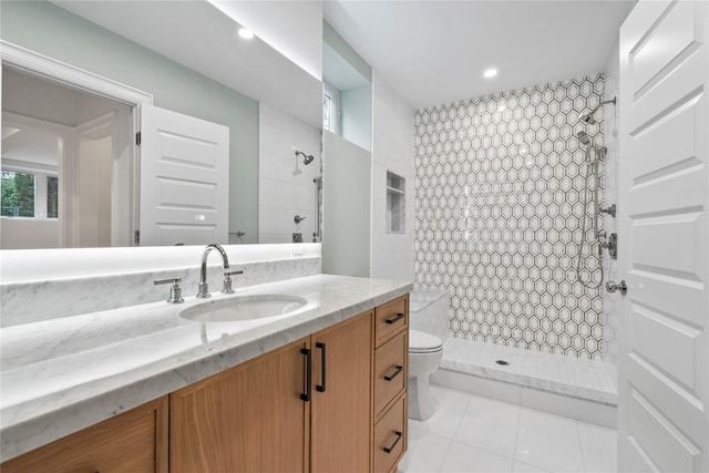 bathroom with vanity, tile patterned flooring, toilet, and tiled shower