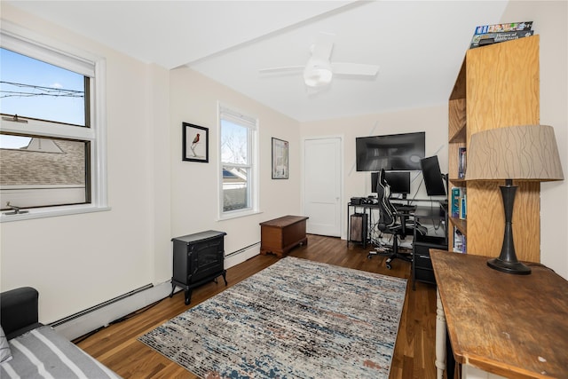 office space with a healthy amount of sunlight, a wood stove, and a baseboard heating unit