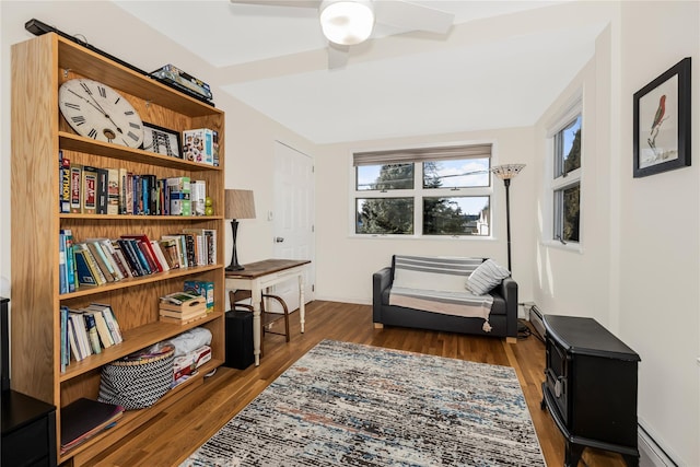 living area with a baseboard heating unit, dark hardwood / wood-style floors, and ceiling fan