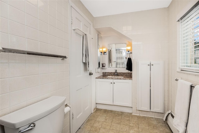 bathroom featuring vanity, tile walls, and toilet