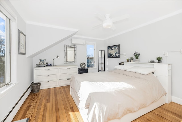 bedroom featuring a wall mounted air conditioner, light hardwood / wood-style flooring, baseboard heating, ornamental molding, and ceiling fan