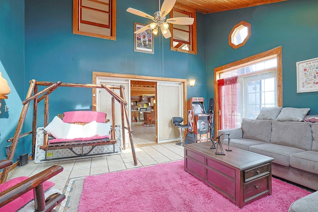 living room featuring light tile patterned floors, ceiling fan, a high ceiling, and wooden ceiling