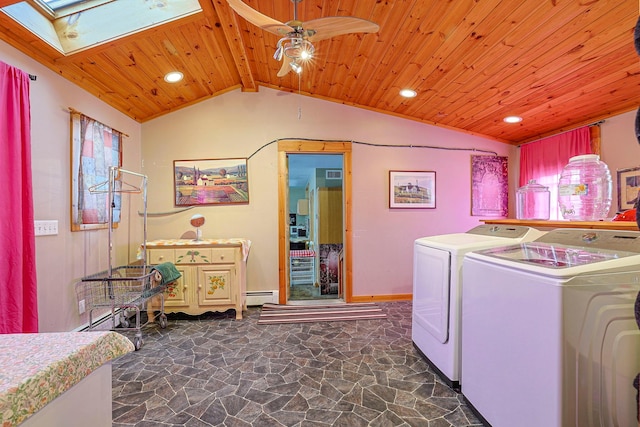 washroom featuring a skylight, washing machine and clothes dryer, baseboard heating, wood ceiling, and stone finish flooring