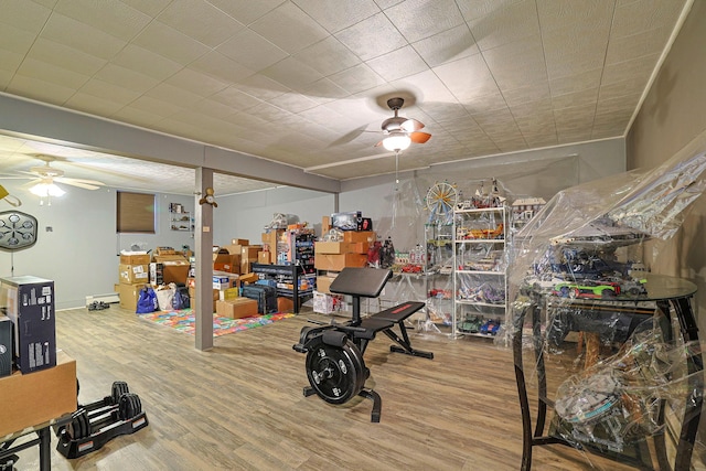 workout area with a ceiling fan and wood finished floors