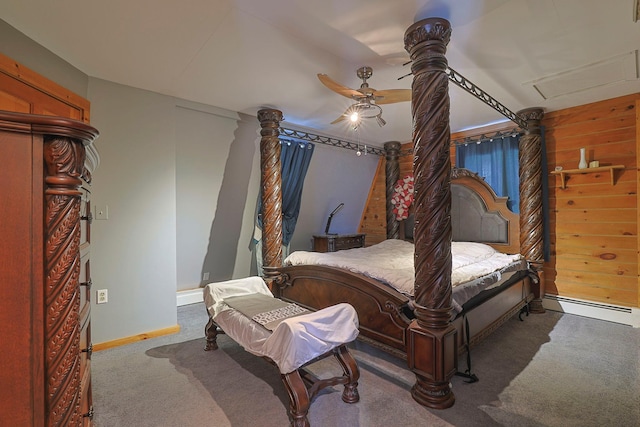 bedroom with carpet floors, a baseboard heating unit, a ceiling fan, wooden walls, and baseboards