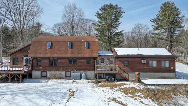snow covered back of property featuring a deck and stairs