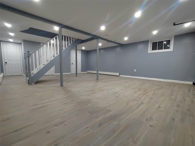 basement featuring baseboard heating and light wood-type flooring