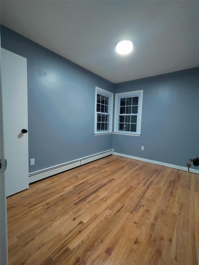 empty room with a baseboard heating unit and light hardwood / wood-style floors