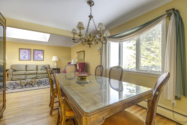 dining space featuring a skylight, a baseboard heating unit, light hardwood / wood-style floors, crown molding, and an inviting chandelier