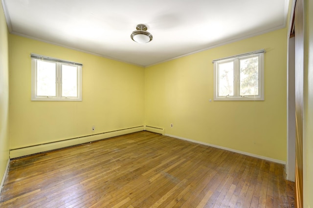 empty room with crown molding, hardwood / wood-style flooring, a wealth of natural light, and a baseboard radiator