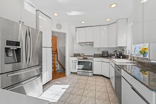 kitchen featuring light tile patterned flooring, sink, white cabinetry, appliances with stainless steel finishes, and dark stone counters