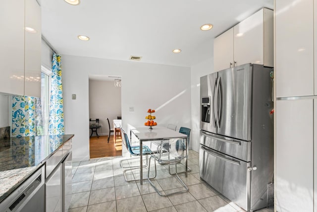 kitchen featuring stainless steel appliances, white cabinetry, light stone countertops, and light tile patterned floors