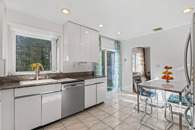 kitchen with stainless steel appliances, sink, light tile patterned floors, and white cabinets