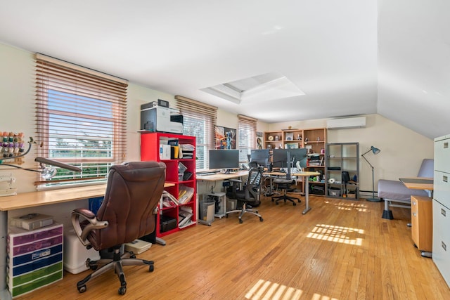 office with lofted ceiling, light wood-type flooring, and a wall unit AC