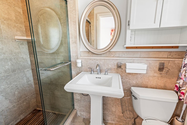 full bathroom featuring a stall shower, toilet, and tile walls