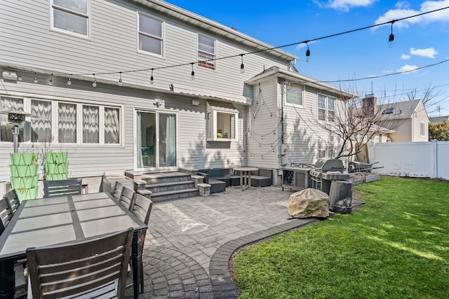 back of house featuring entry steps, fence, a lawn, and a patio