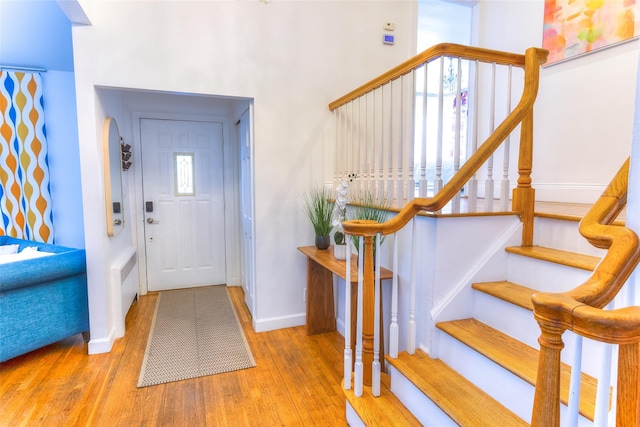 foyer entrance featuring stairway, wood finished floors, and baseboards