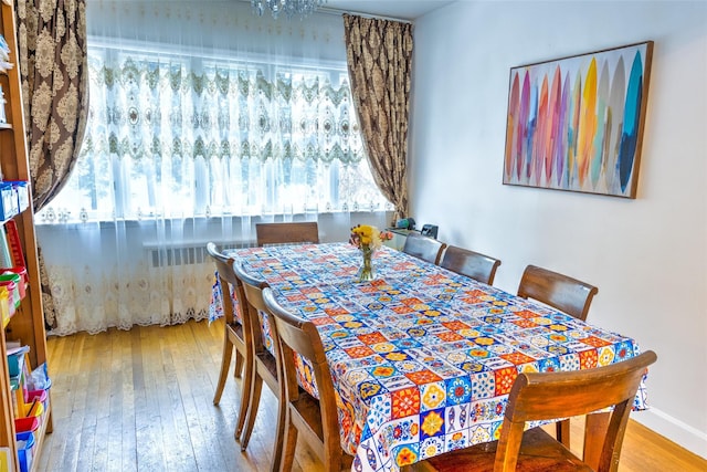 dining area featuring wood-type flooring, baseboards, and radiator heating unit