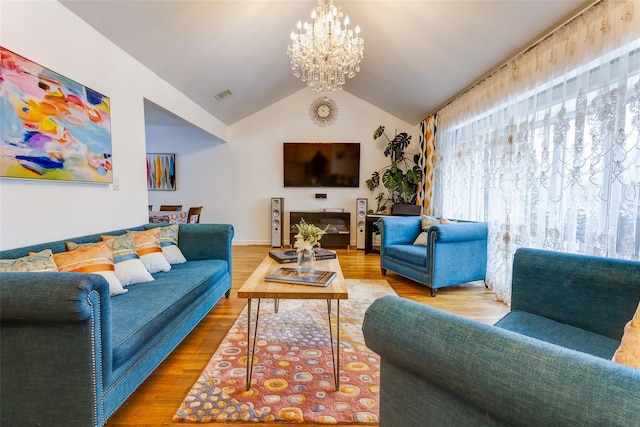 living room with lofted ceiling, visible vents, a chandelier, and wood finished floors