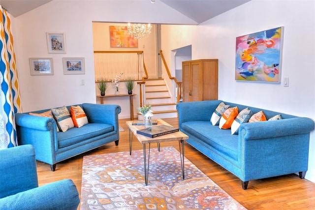 living area featuring lofted ceiling, stairway, wood finished floors, and a chandelier