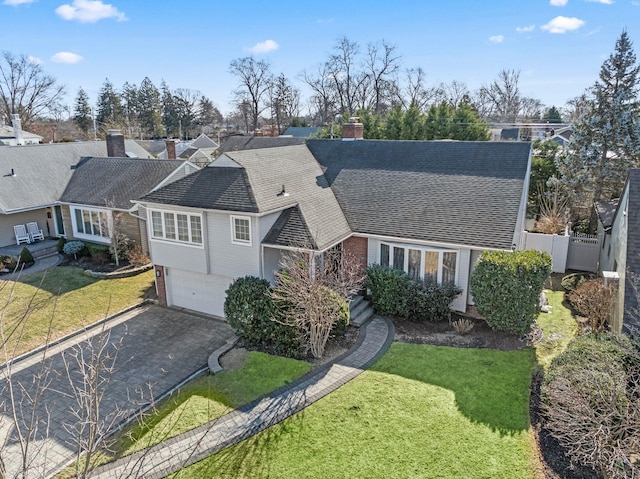 view of front facade featuring aphalt driveway, roof with shingles, an attached garage, fence, and a front lawn