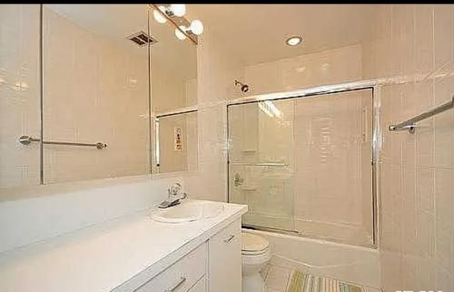 full bathroom featuring vanity, shower / bath combination with glass door, and toilet